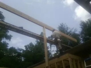 Carpenter setting a ridge beam over a new addition frame — Ice Dam Removal by Roofing Brothers in Kootenai