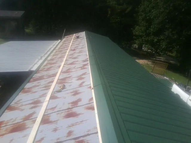 Old rusted panels beside newly installed green metal roofing — Wind Damage Roof Repair by Roofing Brothers in Kootenai