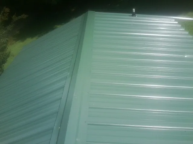 New green metal panels meeting at the ridge of a roof — Flat Roof Repair work by our crew in Kootenai