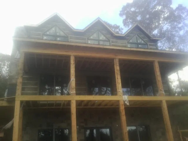 Dormers and porch framing on a large log home under construction — Roof Coating work by our crew in Kootenai