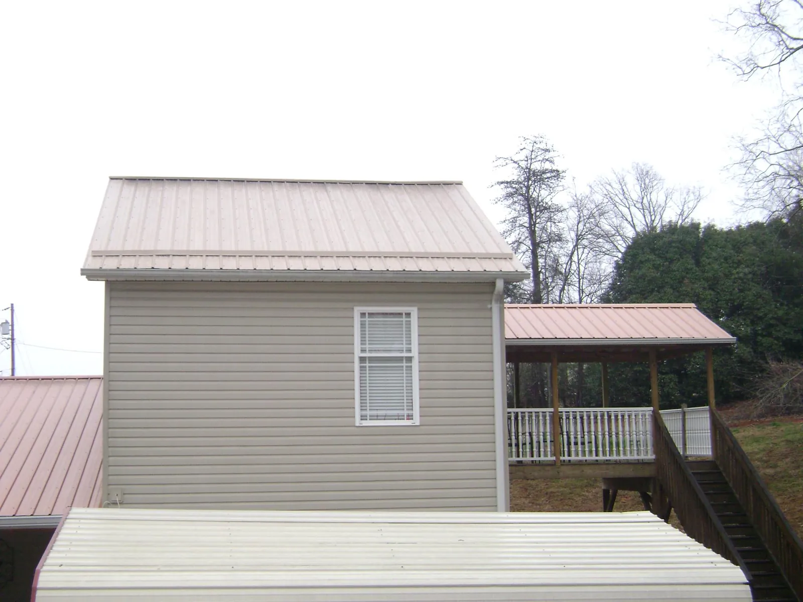 Tan metal roofs on a two story addition and attached porch, from a Roof Replacement job in Kootenai