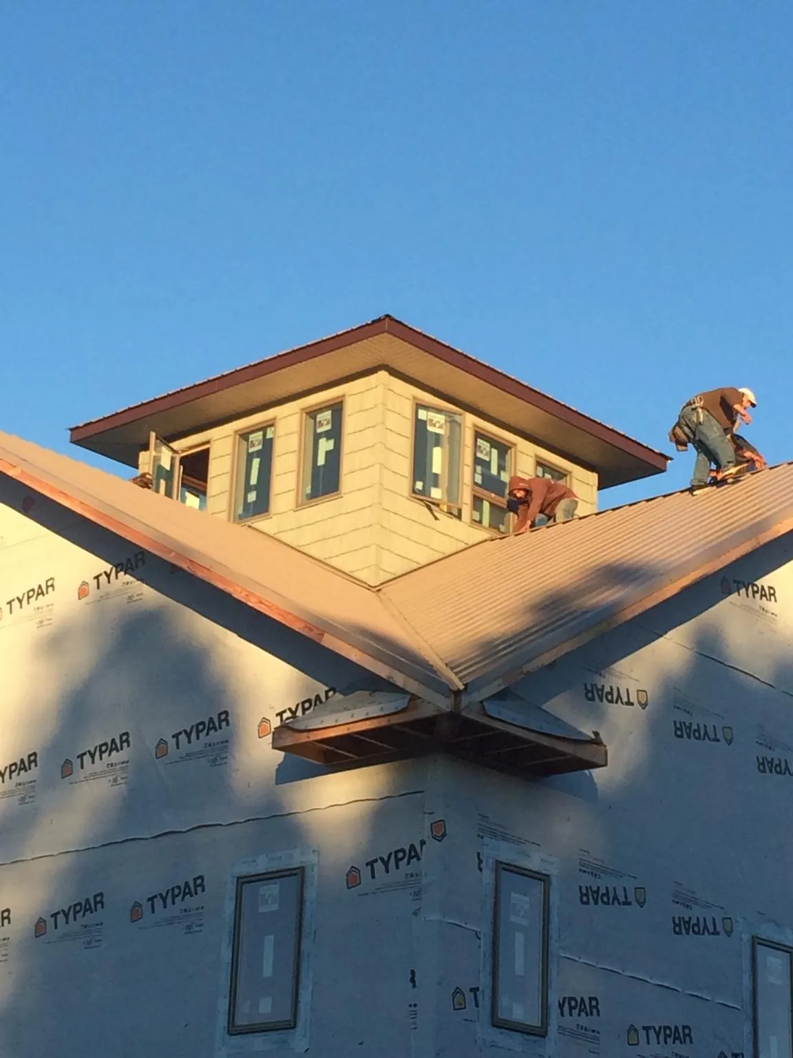 Roofers working around a rooftop cupola on a new metal roof at sunset — Roof Waterproofing in Kootenai by Roofing Brothers